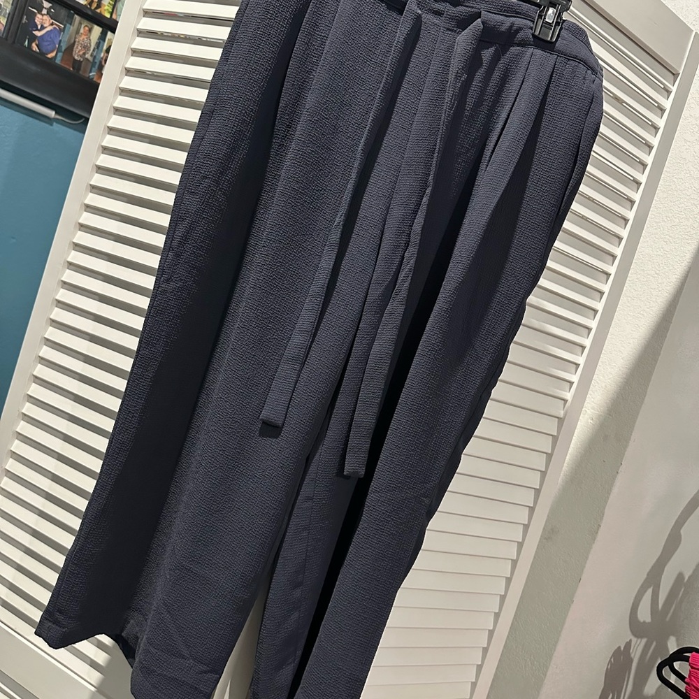 Black dress pants with attached belt.